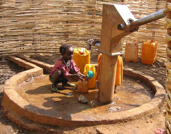 Child collecting water from a borehole with hand pump