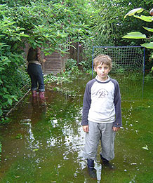 Boy standing in flooded garden