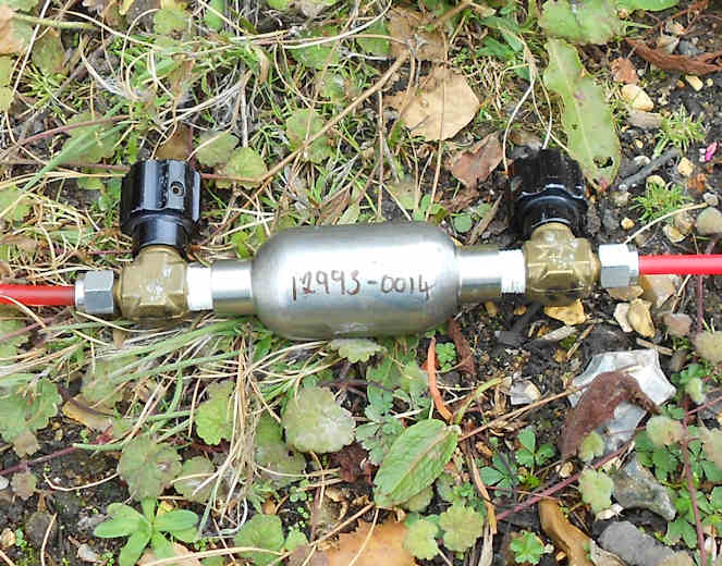 Sampling dissolved gases (including methane) in groundwater: the metal sample container is attached to plastic sampling tubes through which water flows, to ensure an air-tight connection.